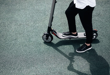 Legs of a man in stylish outfit stand on electric scooter on the street © Leika production