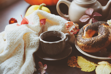 cozy autumn breakfast on table in country house. Hot tea, pumpkins, bagels and flowers.
