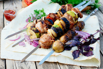 Barbecue. Juicy skewers of pork on pita bread. Decorated with herbs, tomatoes, pickled onion and basil, there is a red sauce next to it.
