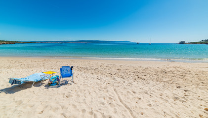 Beach chairs on the sand in Lazzaretto beach in Alghero