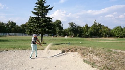 Player man kick the ball from sand bunker on the golf course slow motion