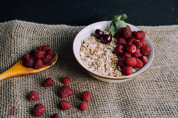 Delicious, healthy breakfast.Porridge with berries.Ecofriendly.Oatmeal porridge with raspberries and cherries.The idea for breakfast on black background. Natural, dietary food.Good morning. Life style