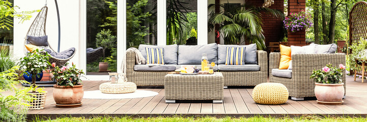 A relaxing spot for a warm, summer day - a stylish, wooden terrace with wicker garden furniture,...