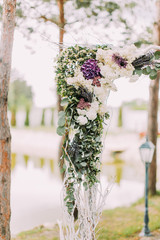 Close-up view of the above part of the wedding arch decorated with colourful flowers and herbs.
