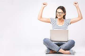 Business concept. Portrait of happy woman in casual sitting on floor in lotus pose and holding laptop isolated over white background.