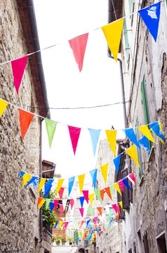 Multicolored festive bunting on narrow old street of a typical european town. Italy