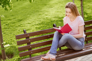  girl with a notebook sitting on a bench in the Park
