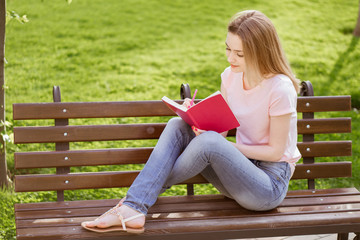 Obraz premium girl with a notebook sitting on a bench in the Park