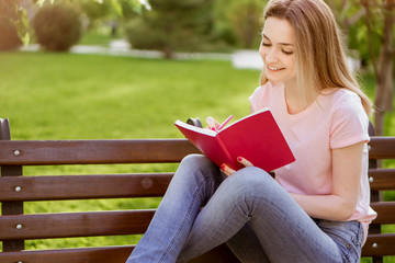  girl with a notebook sitting on a bench in the Park