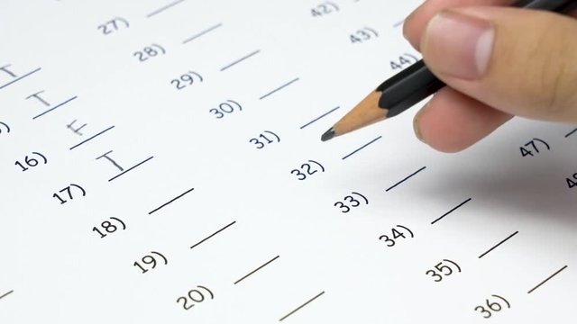 Asian student hand doing True and False examination and student changes his mind by using eraser delete answer test.