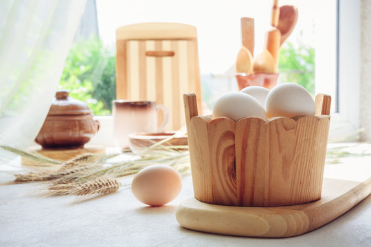 Eggs chicken, cutting boards, spoons, wooden and ceramic tableware on the table near the window for cooking baking, light background, the concept of Easter with copy space in vintage style