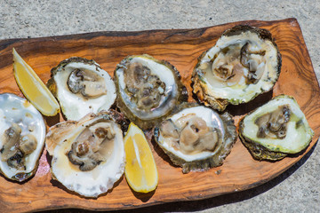 Oysters with lemon on wooden plate. Top view