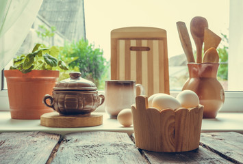 Eggs chicken, cutting boards, spoons, wooden and ceramic tableware on the table near the window for cooking baking, light background, the concept of Easter with copy space in vintage style