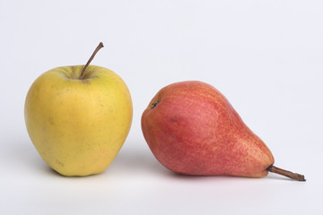 Yellow apple and a red pear on a white table