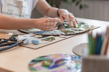 Fototapeta premium Hands of master working on new modern colorful mosaic. Close-up