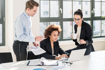 Employees checking together the printed files of a folder with documents and business reports in the office