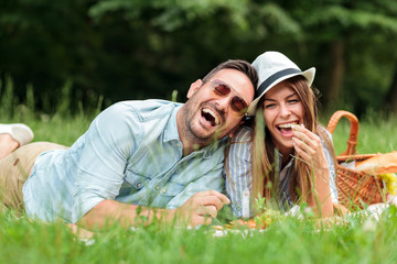 Beautiful happy young couple enjoying their time together, having relaxing picnic in a park. Lying...