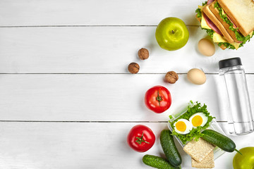 Naklejka na ściany i meble Lunch. Sandwich and fresh vegetables, bottle of water, nuts and fruits on white wooden background. Healthy eating concept. Top view with copy space