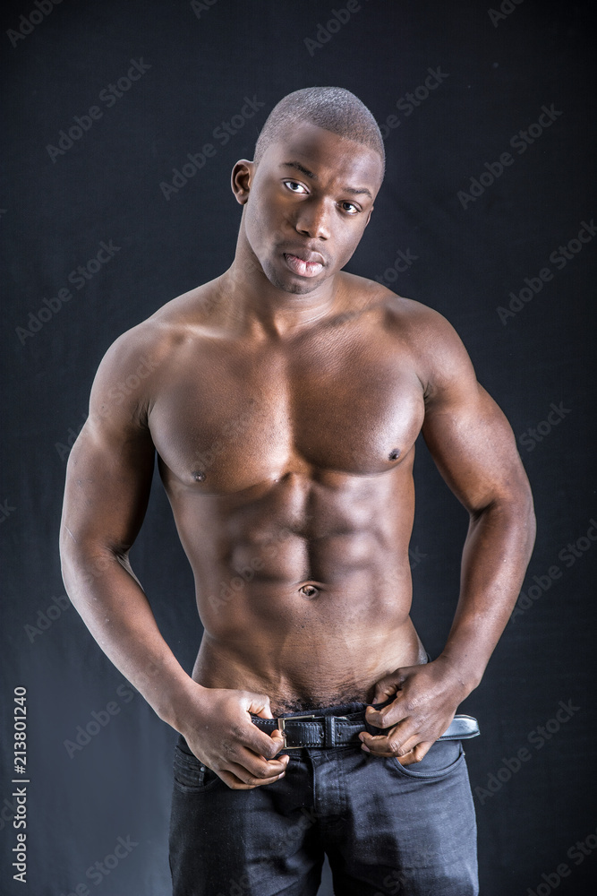 Wall mural Handsome shirtless muscular black young man, looking at camera, on dark background in studio shot