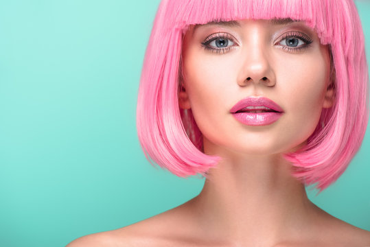 close-up portrait of young woman with pink bob cut looking at camera isolated on turquoise