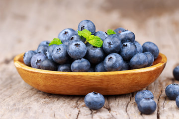 Blueberries in a wood bowl on a wooden table, Healthy eating and nutrition concept