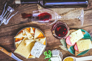 different cheese and a bottle of wine on a wooden background