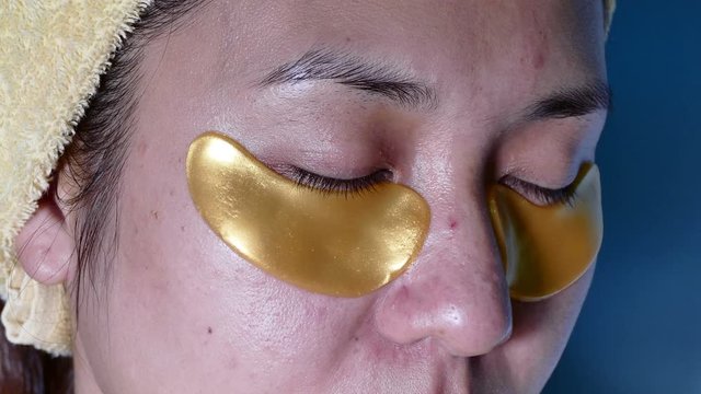 4K Dolly close up Asian girl with golden sticker from eye bags, home spa tretment