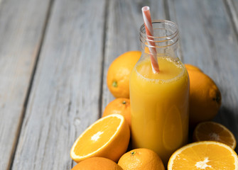 Fresh orange juice in a bottle with oranges on a rustic wooden background