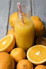 Fresh orange juice in a bottle with oranges on a rustic wooden background