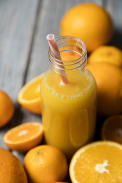 Fresh orange juice in a bottle with oranges on a rustic wooden background