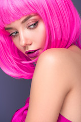 close-up portrait of attractive young woman with pink bob cut isolated on violet