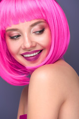 close-up portrait of smiling young woman with pink bob cut isolated on violet