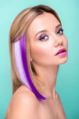 attractive young woman with bobbed hair with purple strands looking at camera isolated on blue