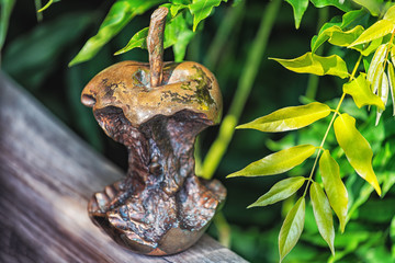 Metal sculpture of apple core with green leaves at the background