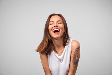 Positive human emotions. Headshot of happy emotional teenage girl laughing, keeping eyes closed, showing perfect white teeth. rejoicing at positive news or birthday gift with charming smile