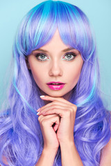 Naklejka premium beautiful young woman with blue hair looking at camera isolated on blue