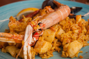 Paella in a light blue ceramic dish decorated by hand