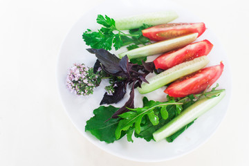 Vegetables and rucola, basil, parsley on a plate. View from above,candid.