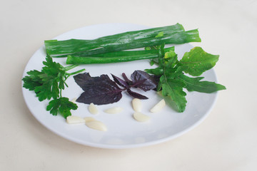Rucola, basil, parsley, arrows onion, garlic on a plate. Candid.