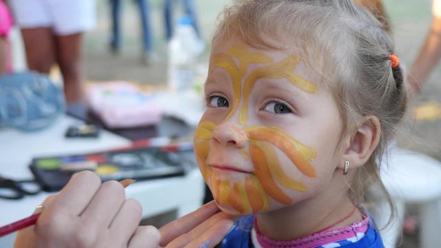 Painting body art on a face of little cute child girl - happy childhood portrait