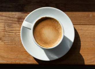 Cup of coffee on wooden background lighten with sun light