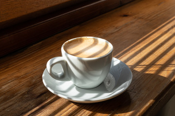 Cup of coffee on wooden background lighten with sun light