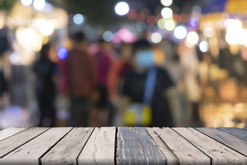 Wooden table on front and blurred night street market background, abstract background