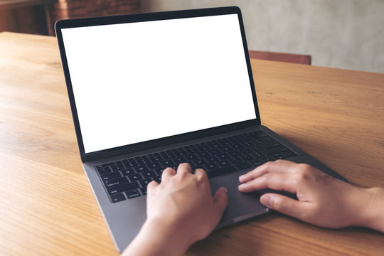 Mockup image of a woman using laptop with blank white desktop screen on wooden table