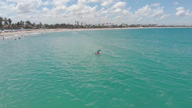 rotating shot of people paddling kayak on the blue sea in Brazil, porto de galinhas