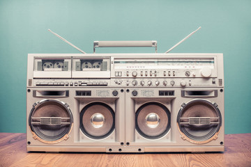 Retro outdated portable stereo boombox radio receiver with cassette recorder from circa 80s front mint green wall background. Listening music concept. Vintage old style filtered photo