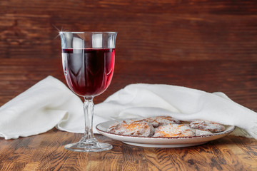 red wine in a steamed glass on a high leg on the background of a plate with cookies and towels