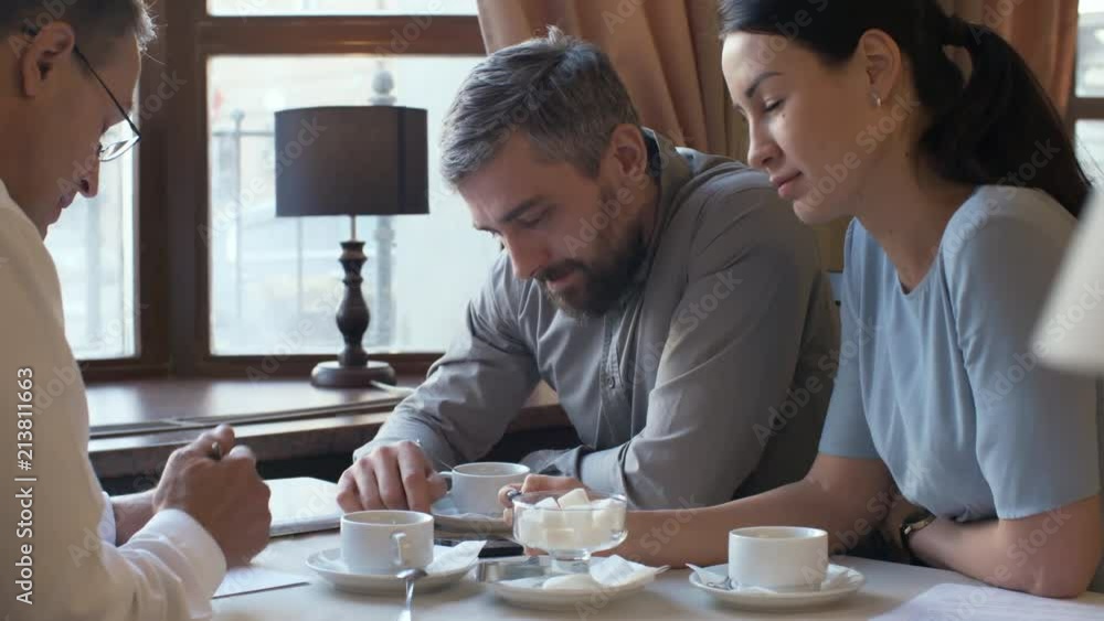 Poster medium shot of three entrepreneurs discussing work at business lunch, two of them talking about cont