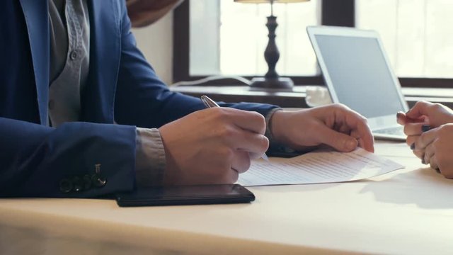 Hands of unrecognizable entrepreneur in business suit discussing contract with female colleague before signing it