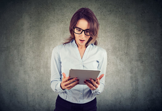 Young woman looking shocked while using tablet